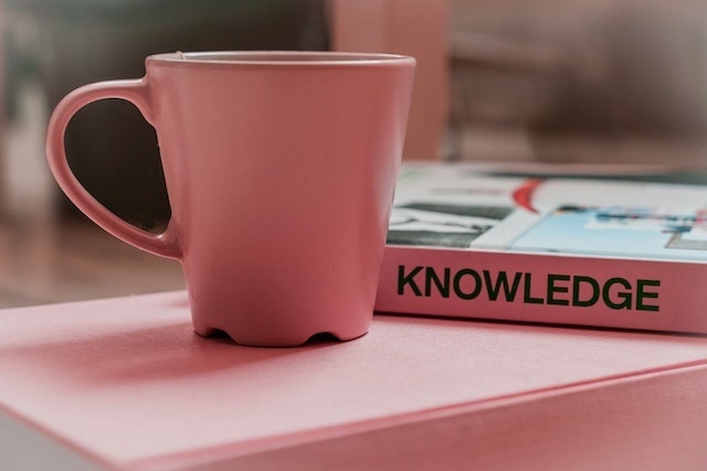 Pink tea mug next to book