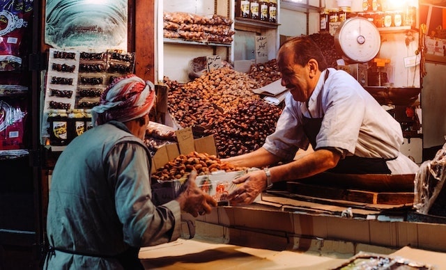 Shop owner handing a box of goods to a customer.