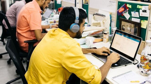 Three men working at laptops