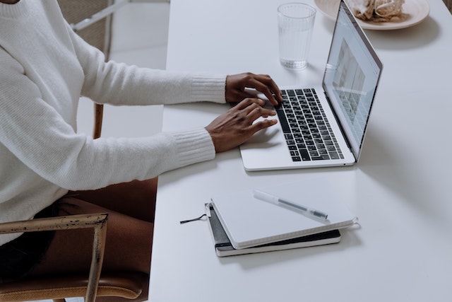 Woman working on a laptop while sitting at a desk.