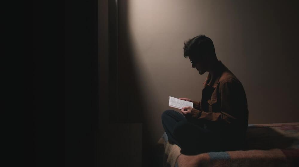 Man reading a book on a bed