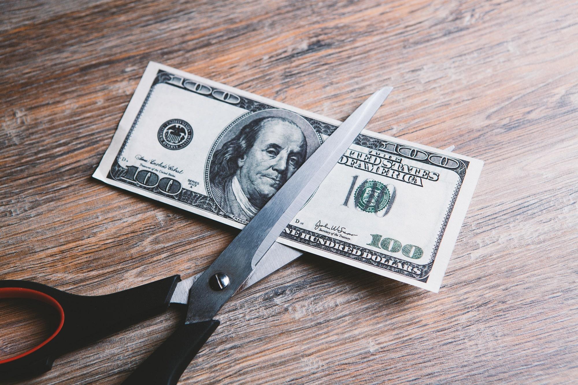 Scissors resting on a $100 US dollar bill