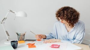 Woman looking at receipts on desk with pink calculator nearby