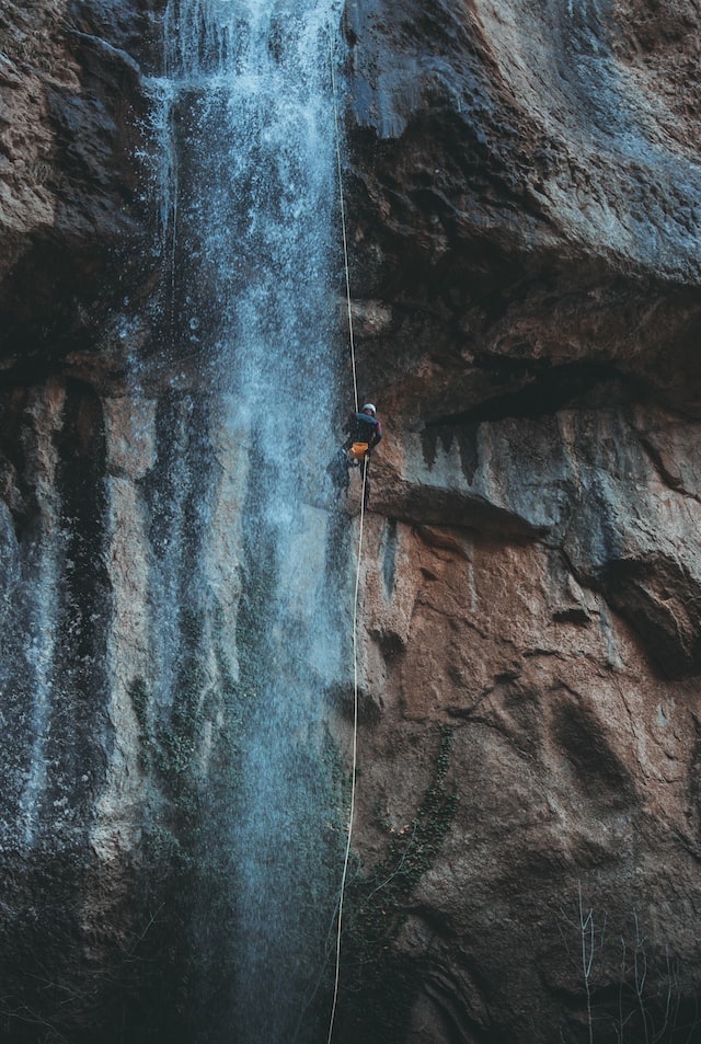 Climber dangling from a rope at a waterfall