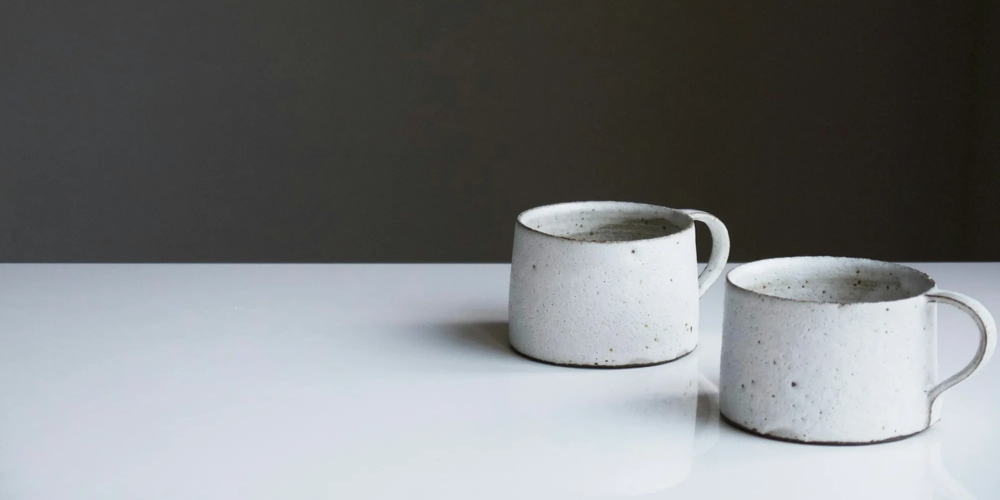 Two white ceramic mugs on a white table