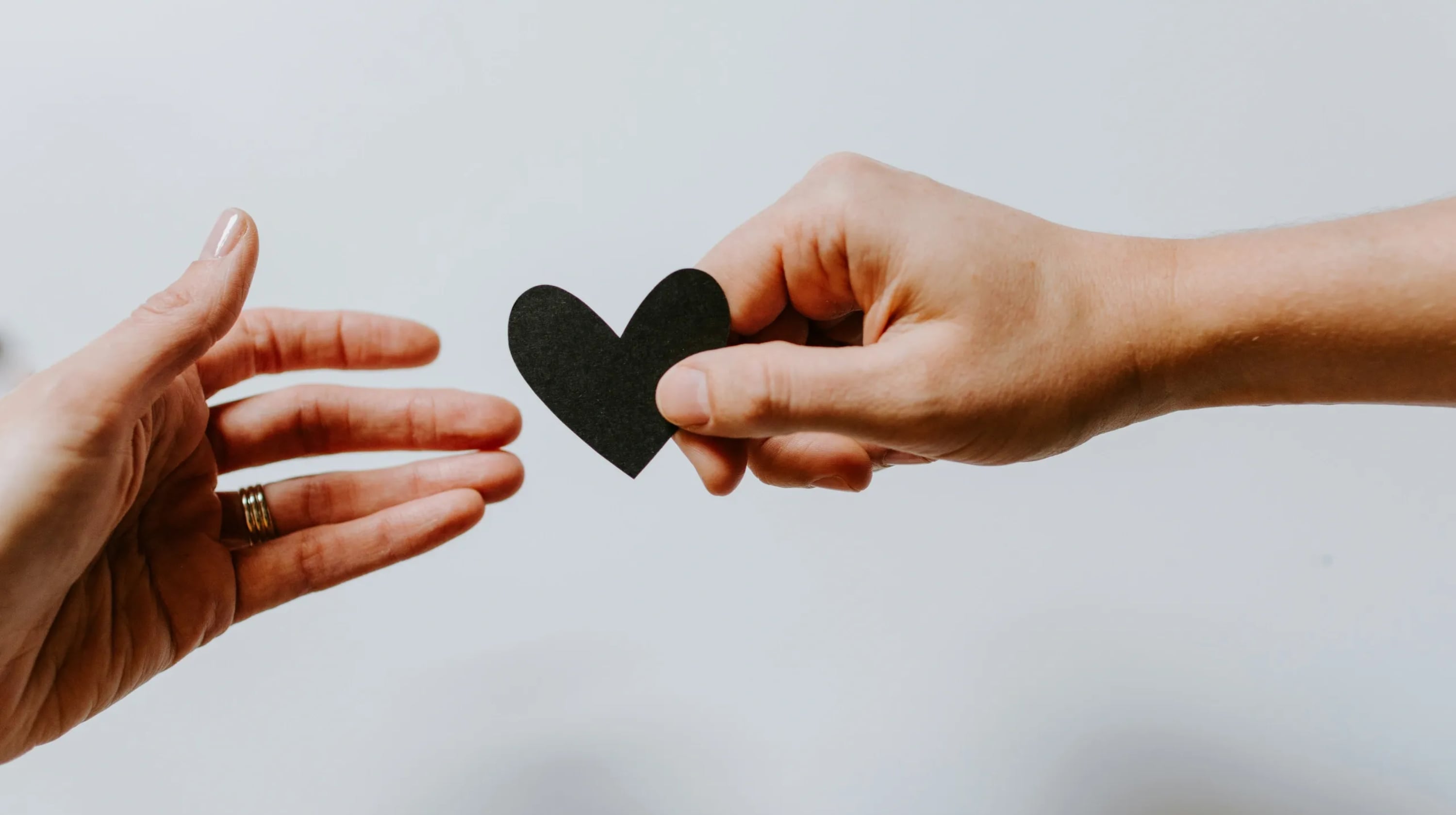 Person handing another person a paper heart