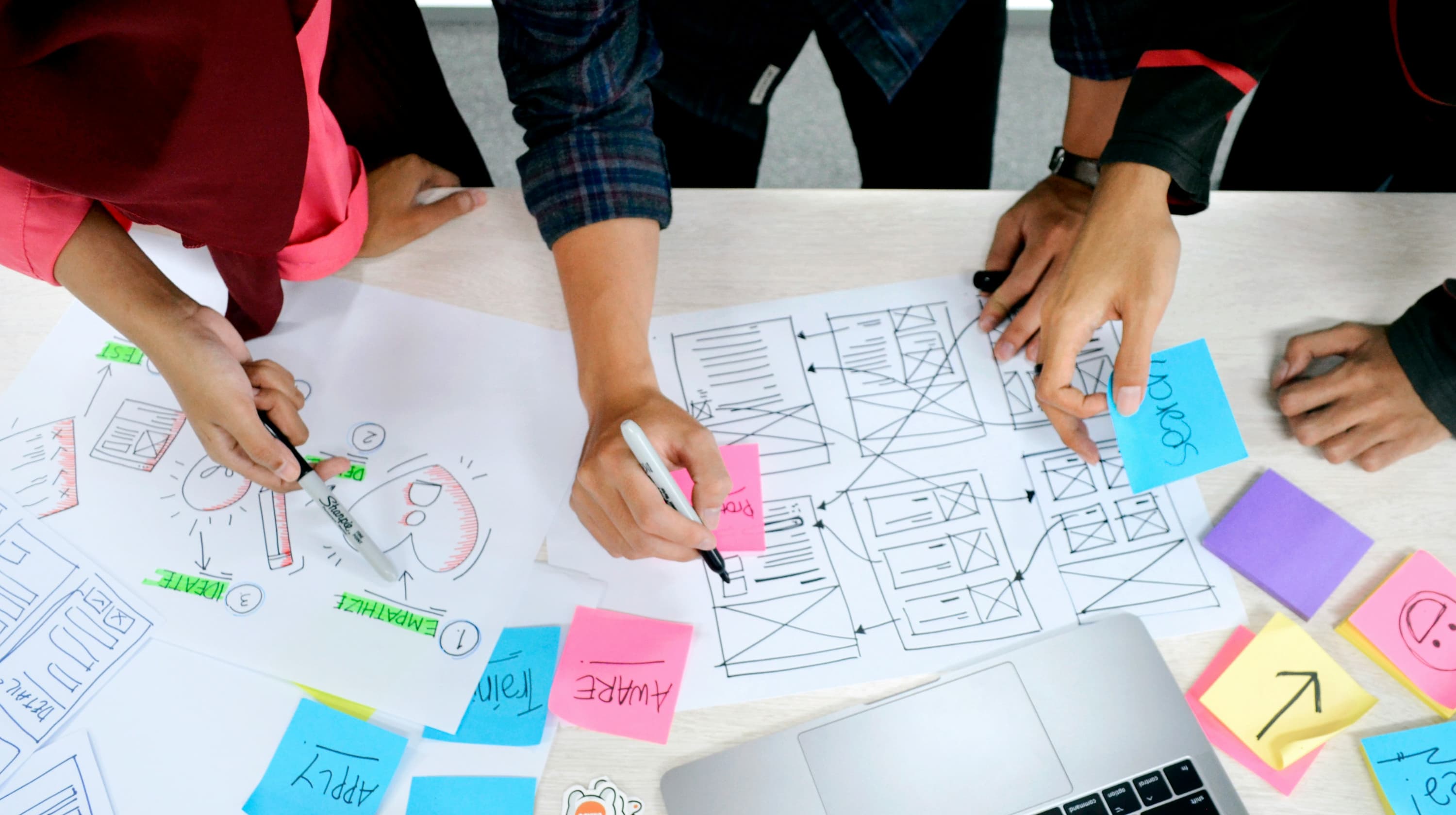 Three people working on landing page sketches