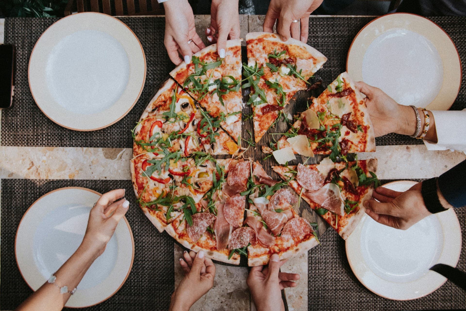 People reaching for slices of pizza