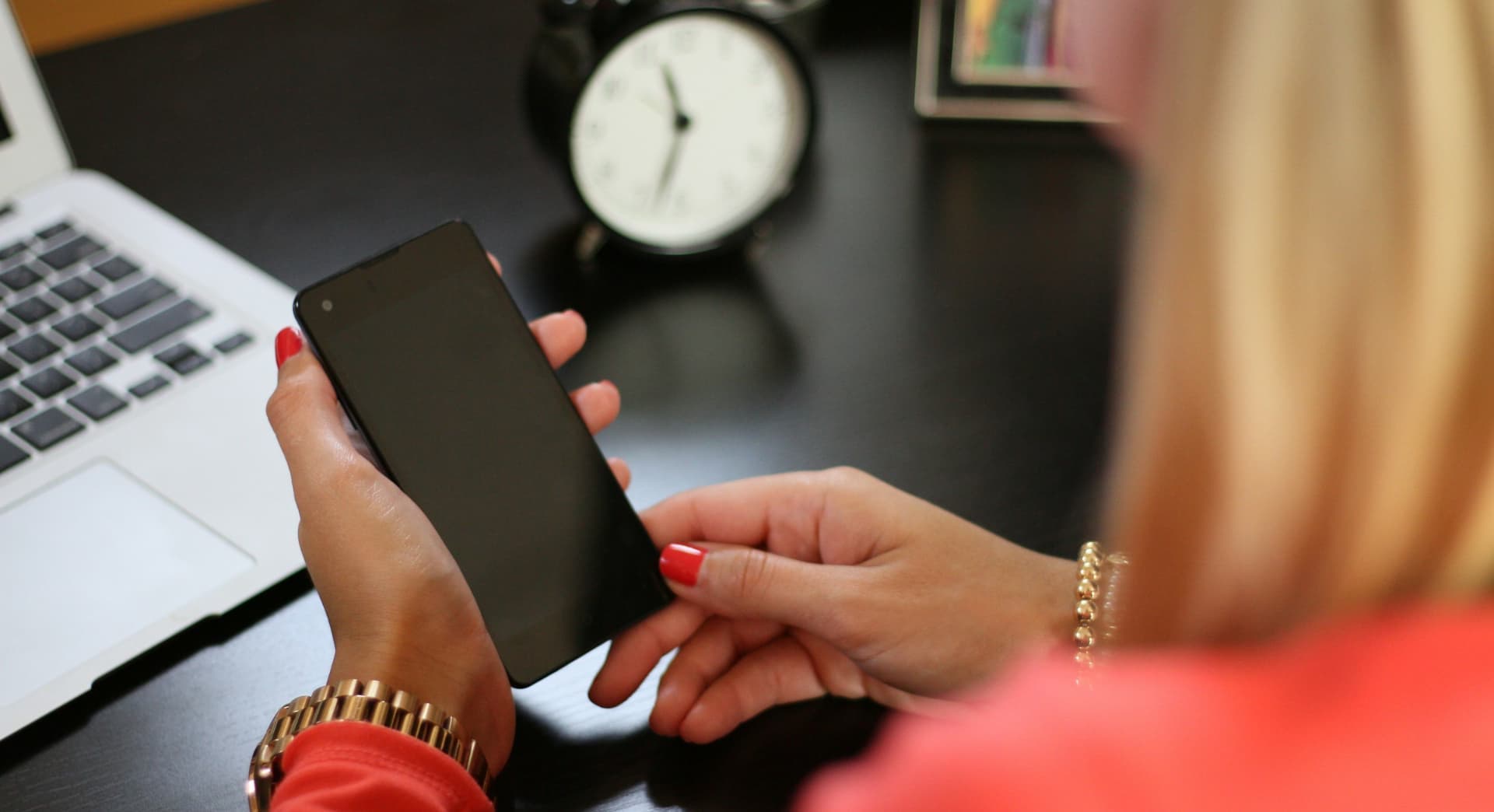 Woman sitting at a desk opening her phone