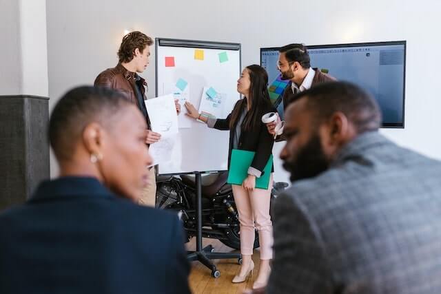 Three people standing near a white board