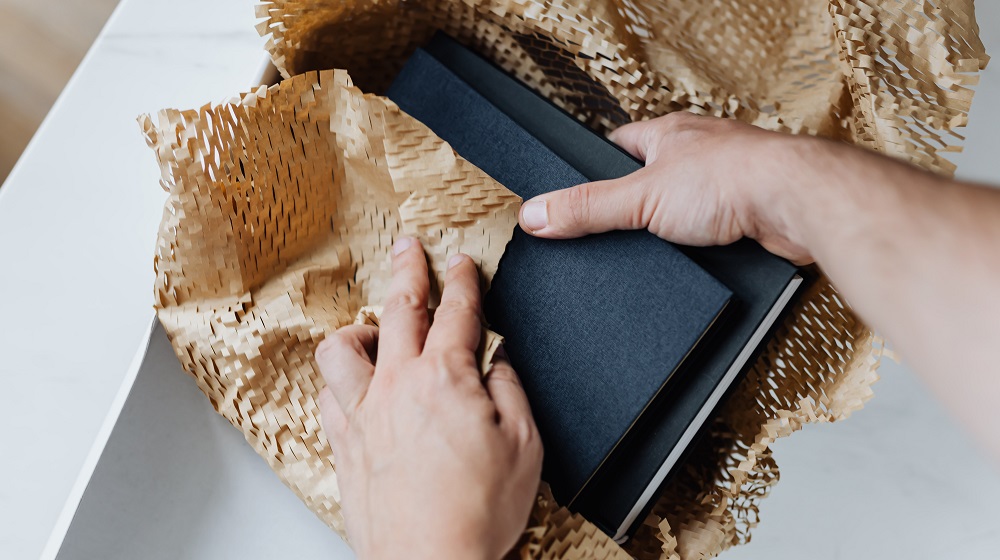 person packing books into shipping container