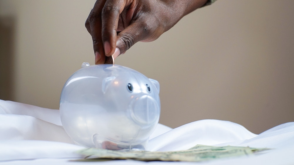 Person Putting Coin In Piggy Bank