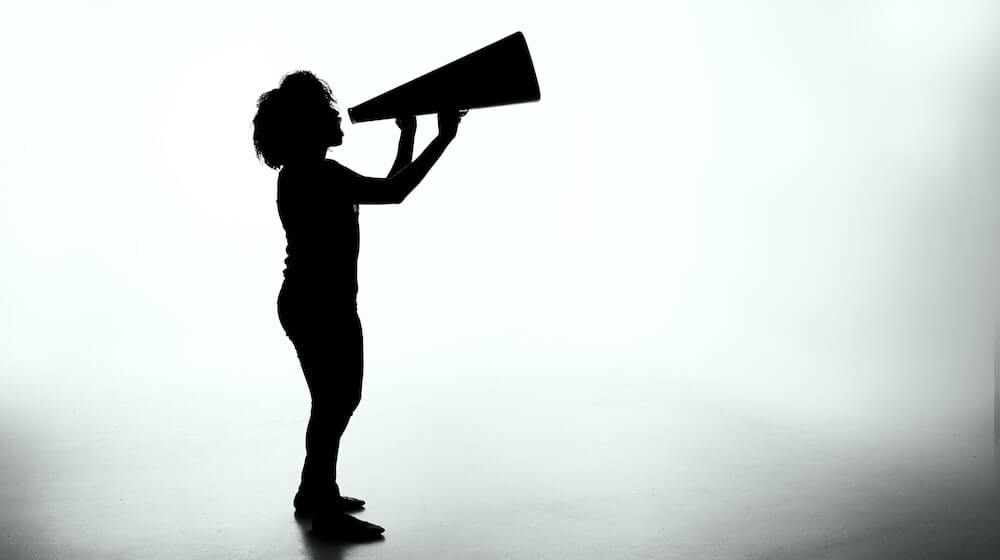 Silhouette of woman yelling into megaphone