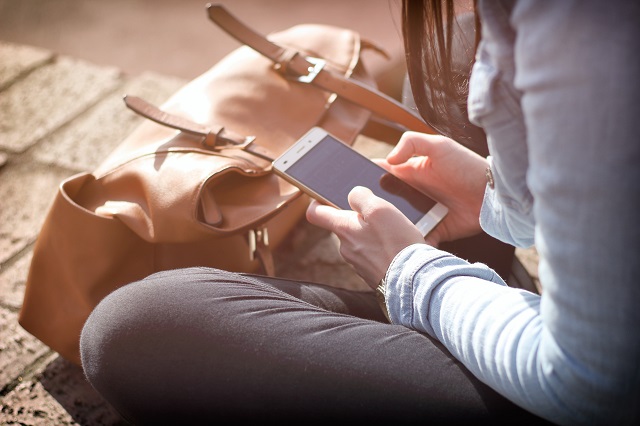 Person sitting on the ground using a smart phone