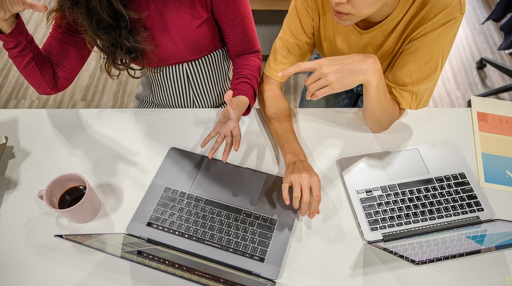 Two women conversing over laptops