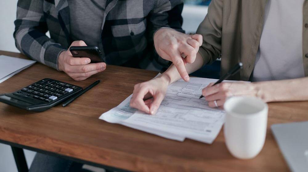 Two people looking over documents with a calculator