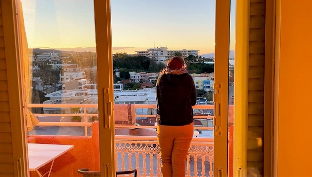 Photo of writer overlooking a balcony with Mediterranean city in background.