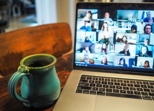 A mug resting next to a laptop with the screen full of Zoom thumbnails