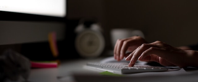 Photograph of person typing in a dimly-lit room