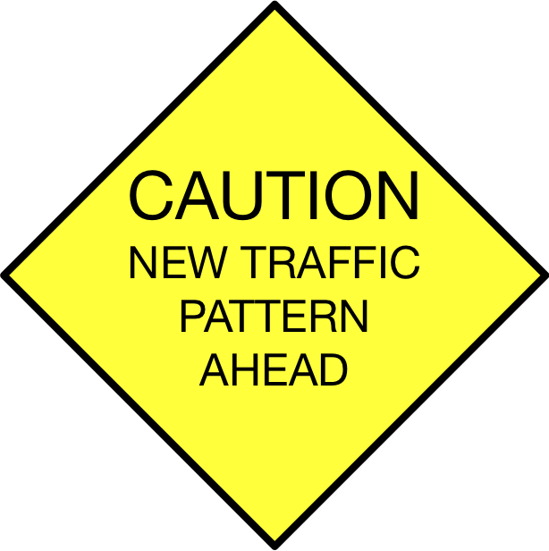 A cautionary yellow sign with a diamond shape, indicating an upcoming change in traffic pattern