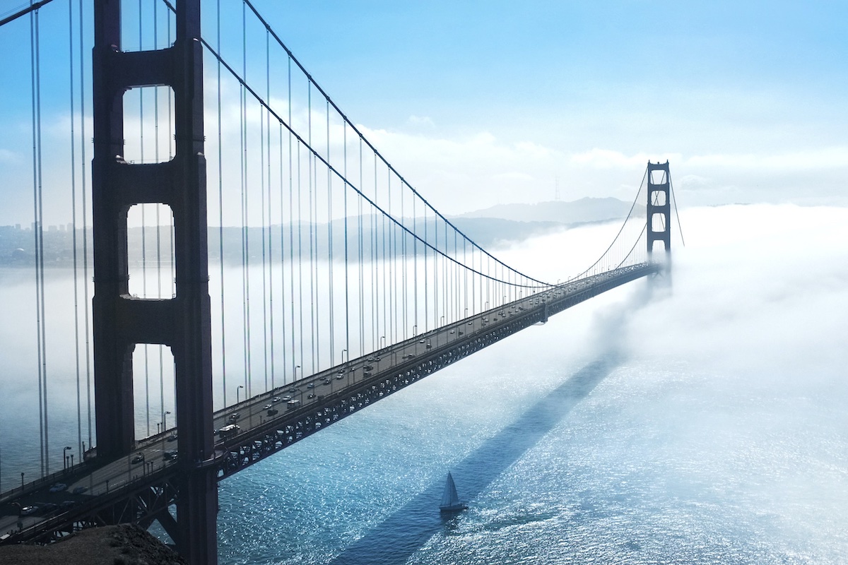 Golden Gate Bridge over water with cars and a sailboat