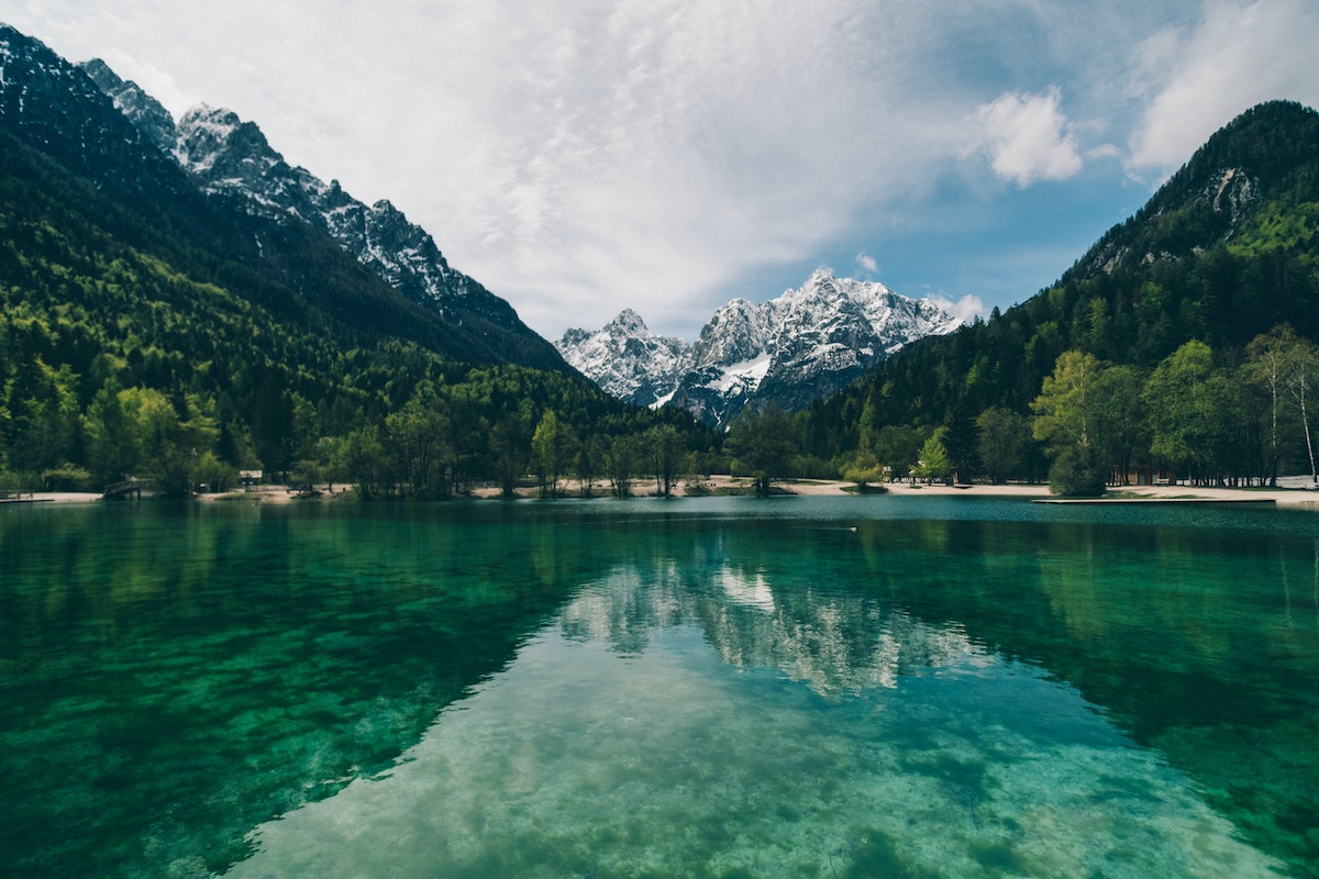 A body of water with trees and mountains in the background