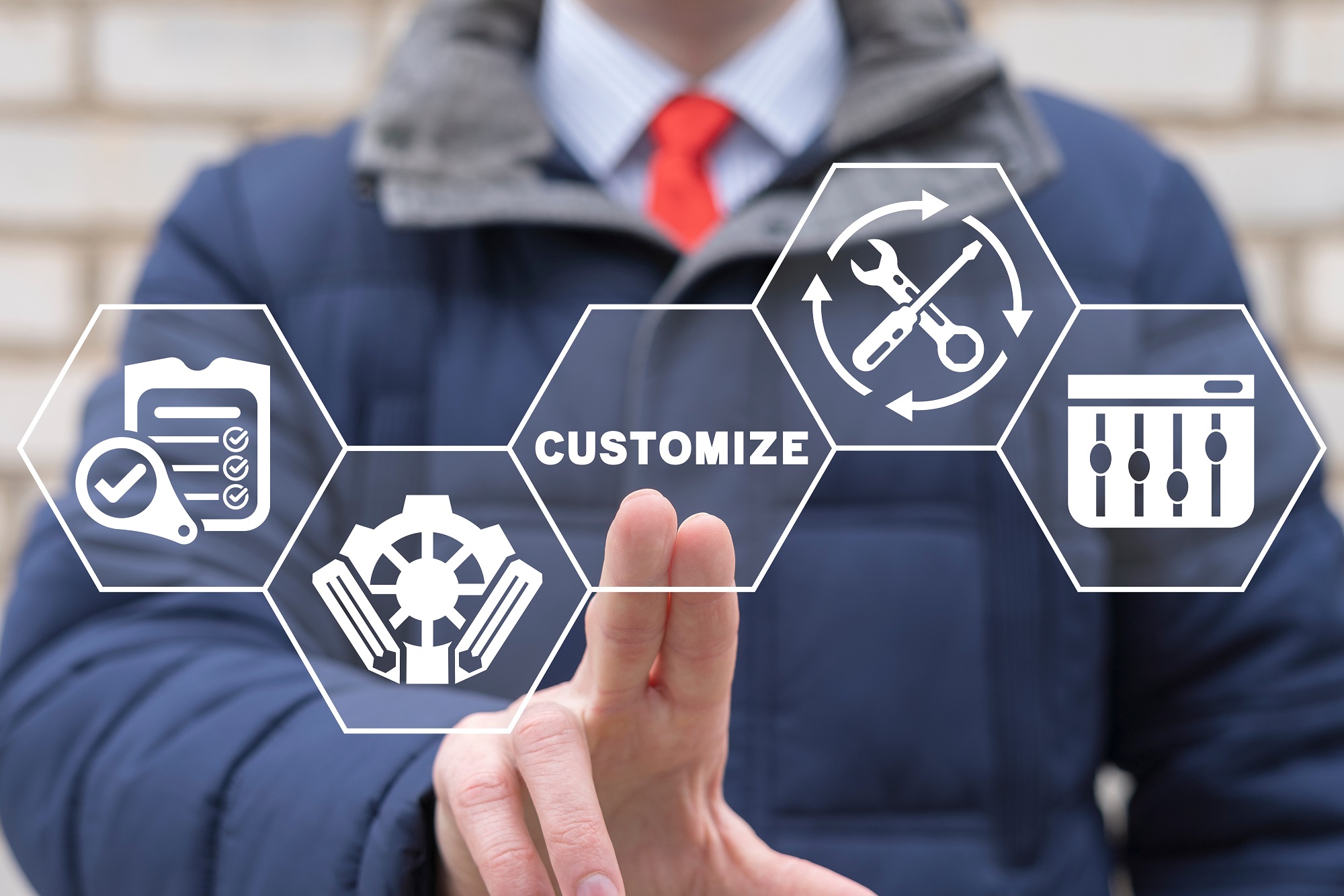 A person in a blue jacket and red tie is touching a virtual interface with the word &quot;CUSTOMIZE&quot; at the center, surrounded by icons representing customization options such as a checklist with a magnifying glass, a wrench and screwdriver, gears, and a control panel with sliders.