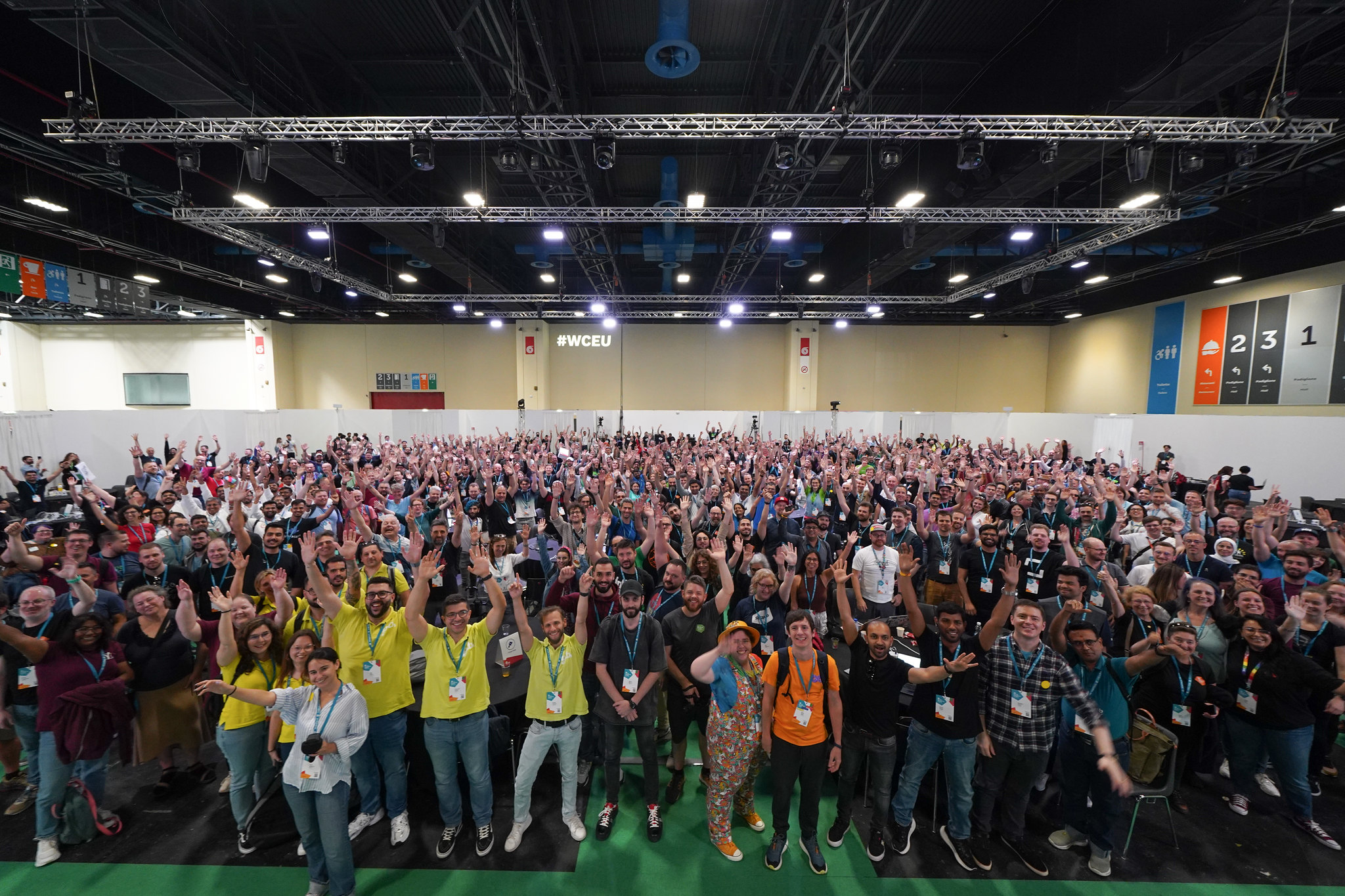 Participants at WordCamp Europe 2024 Contributor Day gather for a group photo around tables.