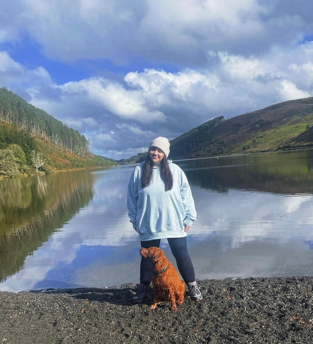 a person standing on a rock by a body of water with hills in the background