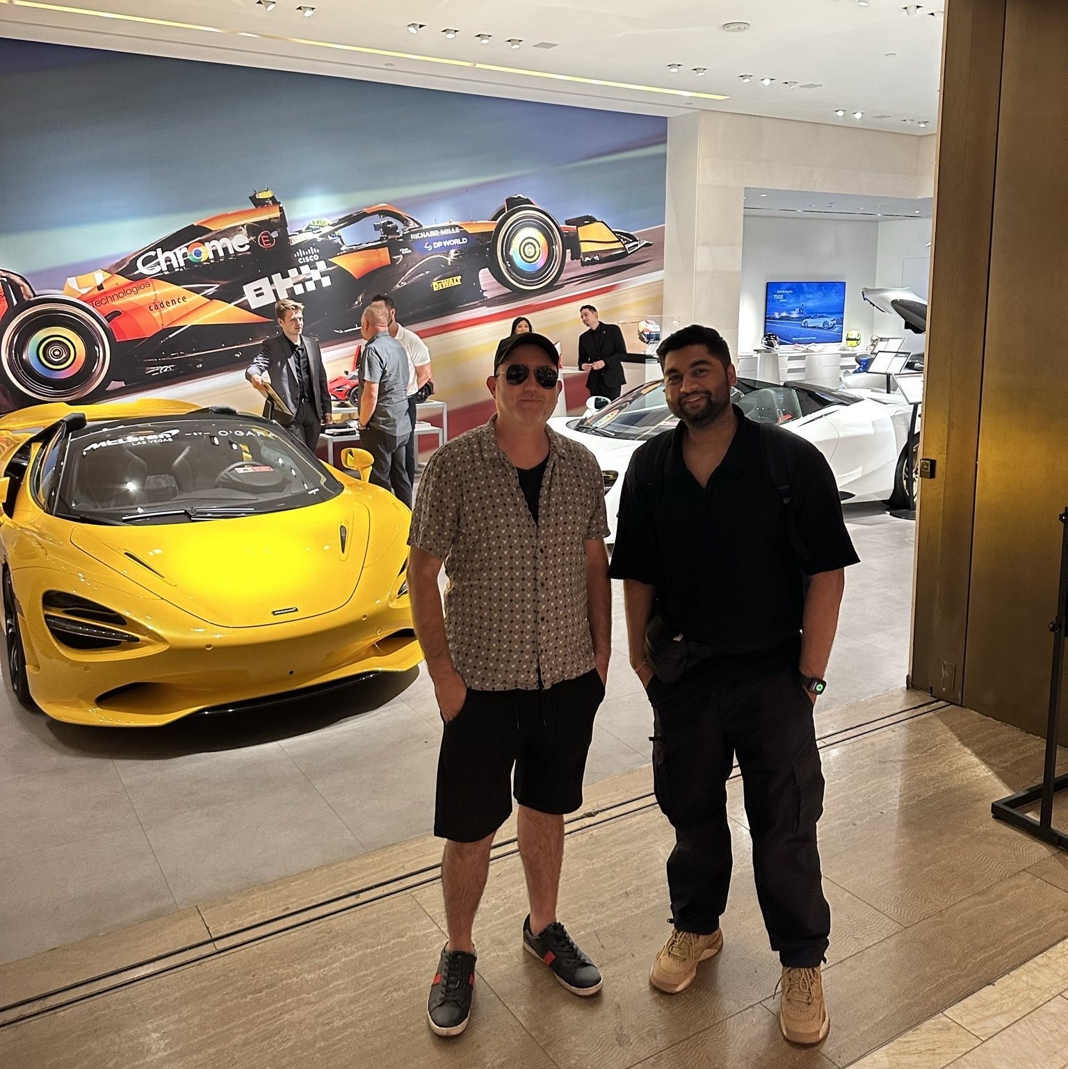 two men standing in front of a yellow sports car in a showroom