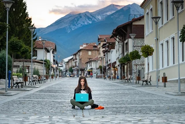 a person sitting on a street with a laptop