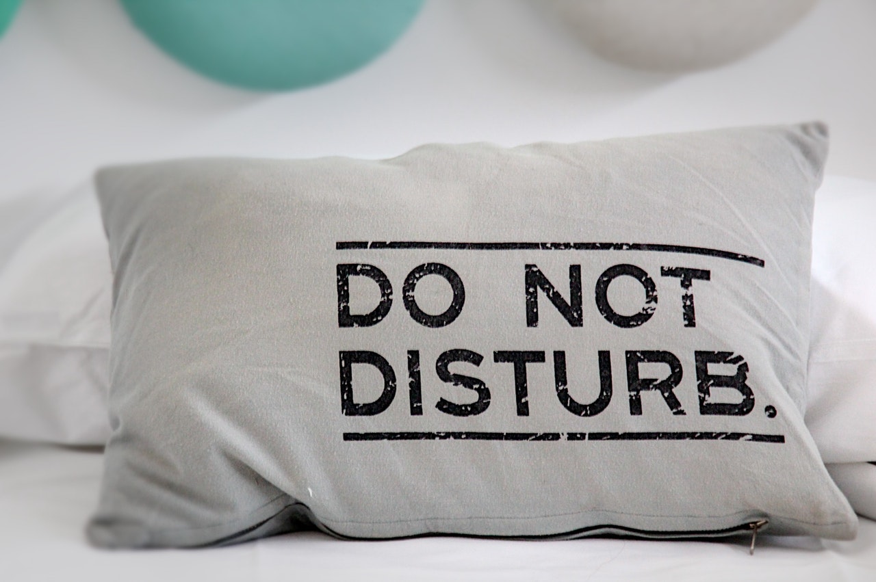 white pillow with printing "do not disturb" on a bed